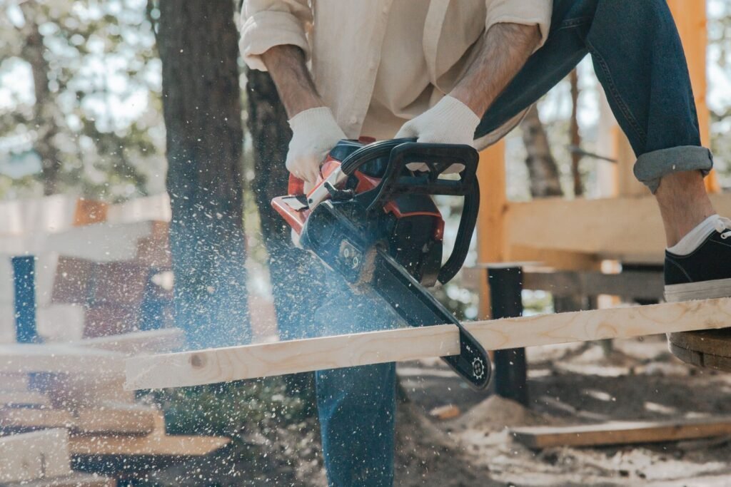 Utilisateur sciant une pièce de bois à la tronçonneuse en extérieur